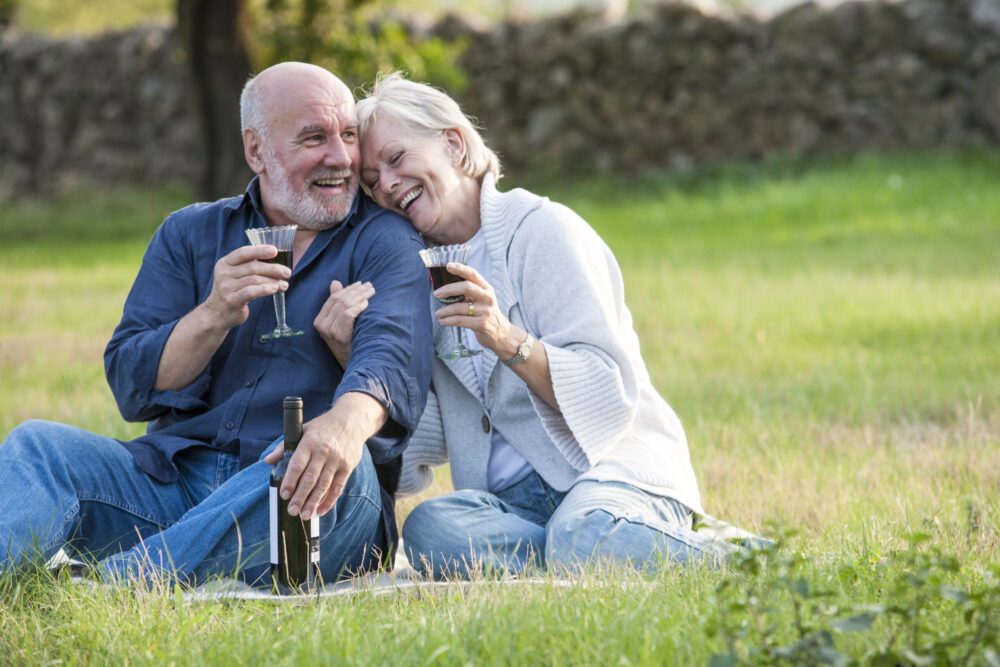 Senior couple outdoors, sitting on blanket enjoying life's small pleasures