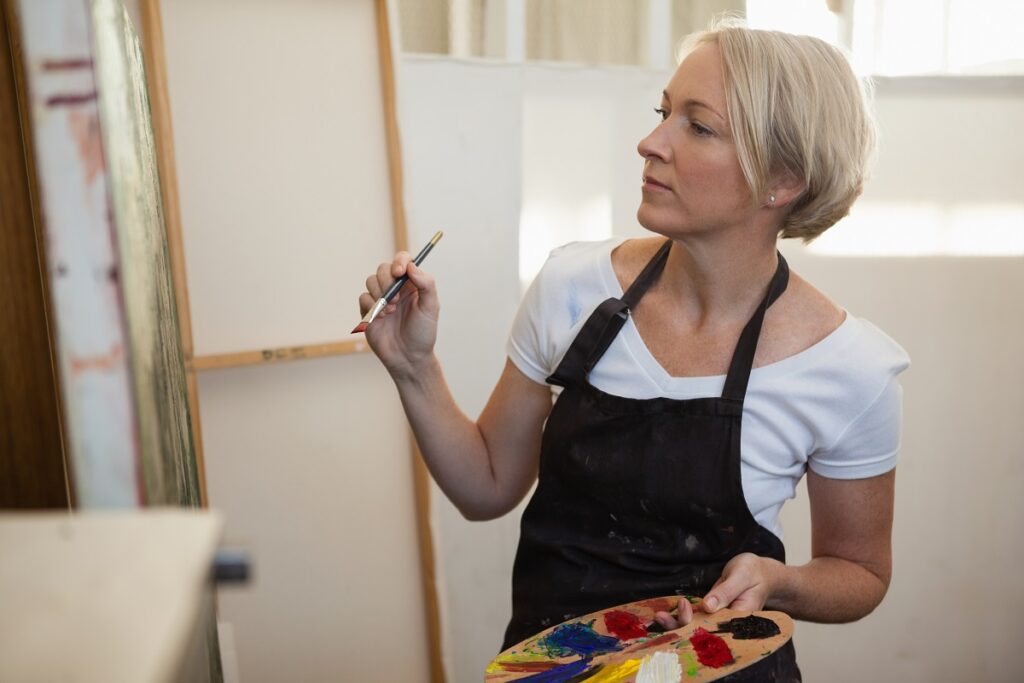 Woman painting on canvas in drawing class