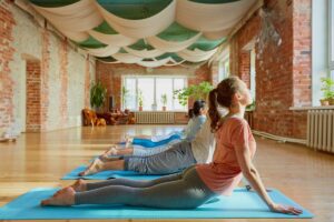 fitness, yoga and healthy lifestyle concept - group of people doing cobra pose on mats at studio