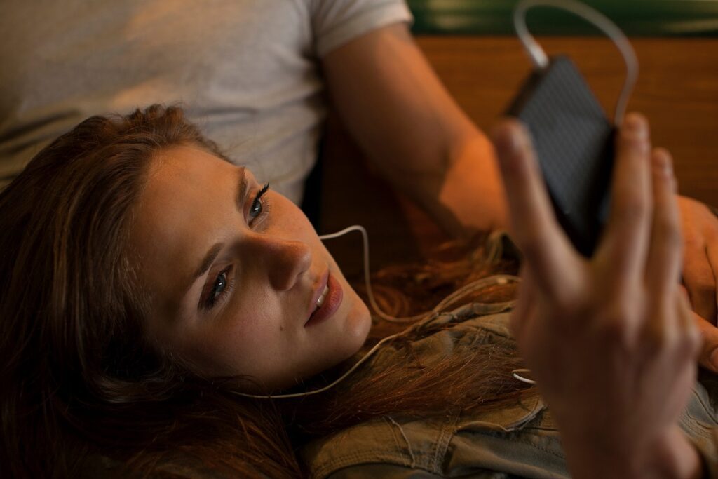Young woman listening to music, lying on boyfriend's lap