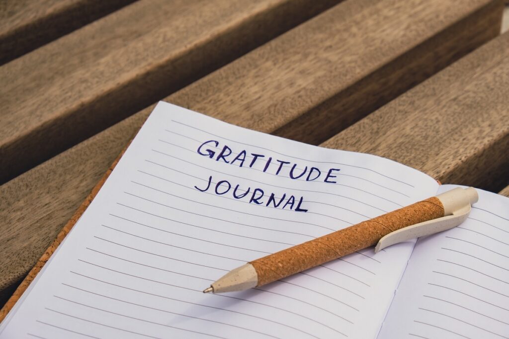 Writing Gratitude Journal on wooden bench. Today I am grateful for. Self discovery journal, self reflection creative writing, self growth personal development concept. Self care wellbeing spiritual health, being mindful, holistic health practices habits mindfulness